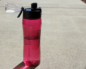A pink water bottle on the ground.