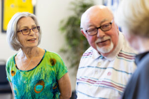 A group of three older people are pictured talking together in an engaged and friendly way