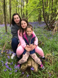 Ukrainian refugee cuddles her daughters on a bluebell walk in East Sussex