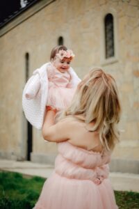 Mother holding up smartly dressed baby in the air.