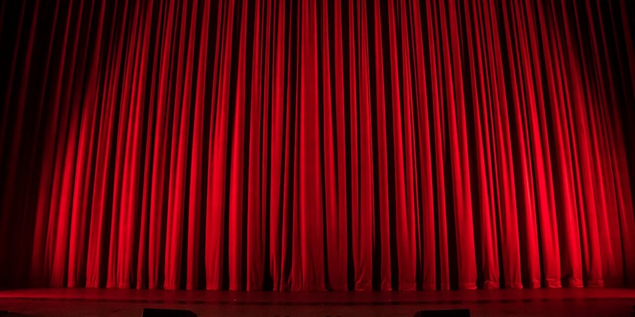 Red theatre curtain with lights shining on it