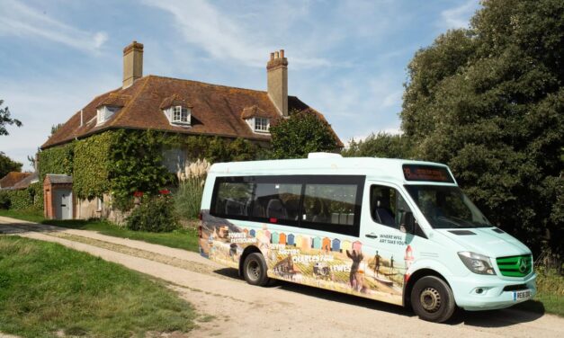 Small bus in front of a period cottage on a sunny dat