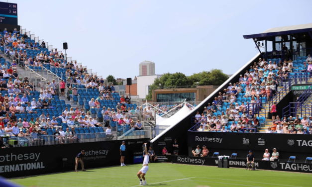 tennis player serving in front of stands full of people