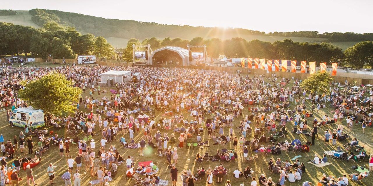 Field at sunset with tents and stage in background