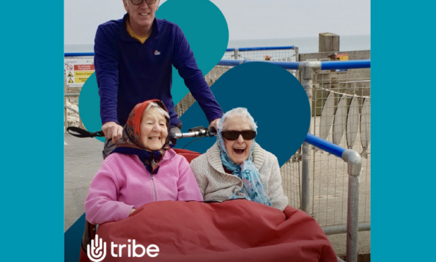 two woman laughing as they're pushed on a wheelchair by a man