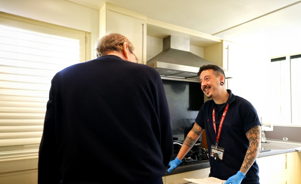 An older man receiving support from a support worker.