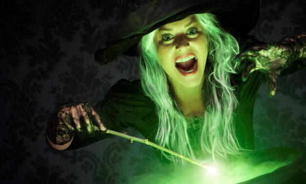 woman dressed as witch casts a spell over a cauldron