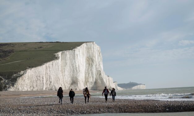 People walking along the beach with white cliffs in the background