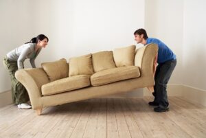 Two people moving a sofa. 