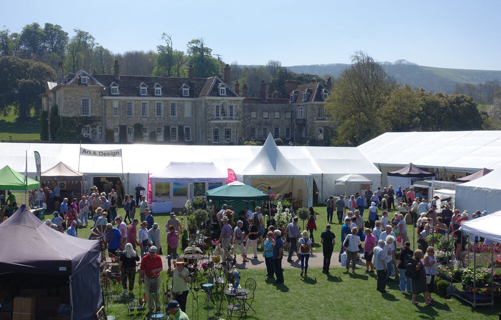 marquees and people on a sunny day in front of a country house