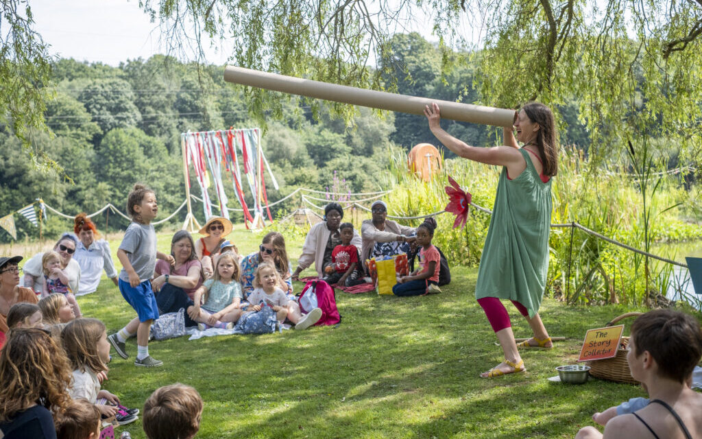 children sitting in a tree glade watching a performer