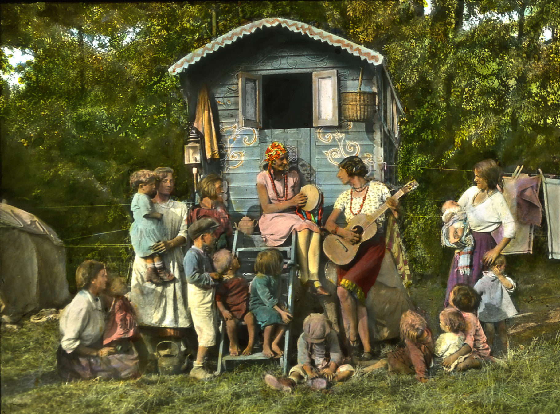 A group of people from the GRT community sit together and play music by their caravan.