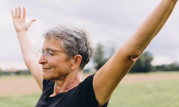 An older woman with her eyes closed and arms outstretched.