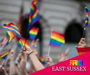 a number of hands wave rainbow flags in the air