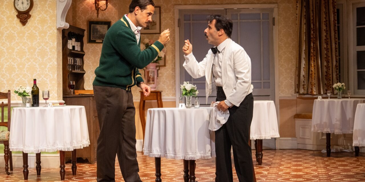 two men on stage in front of table arguing