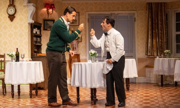 two men on stage in front of table arguing