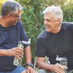 Two mature men smile and chat together