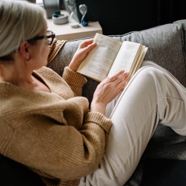 Woman sitting on sofa reading book